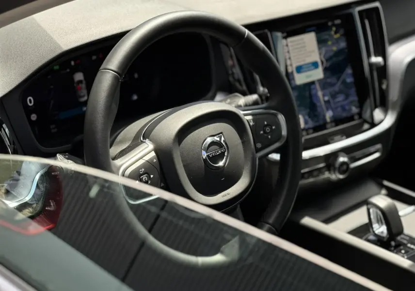 Intérieur de la Volvo S60 rouge Fusion, vue rapprochée du volant et de l'écran tactile central lumineux.