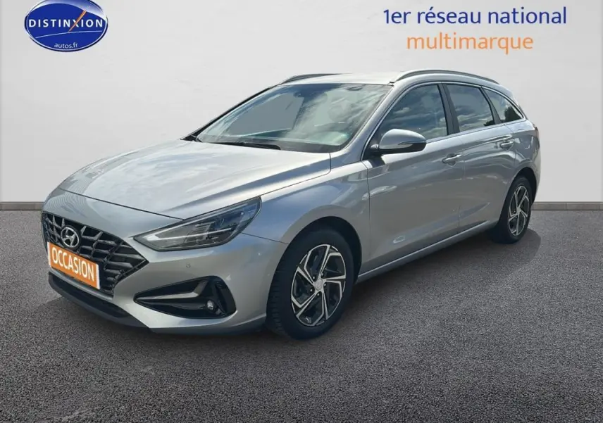 Hyundai i30 SW gris clair vue 3/4 avant droit avec jantes alliage 17 pouces sur fond neutre.