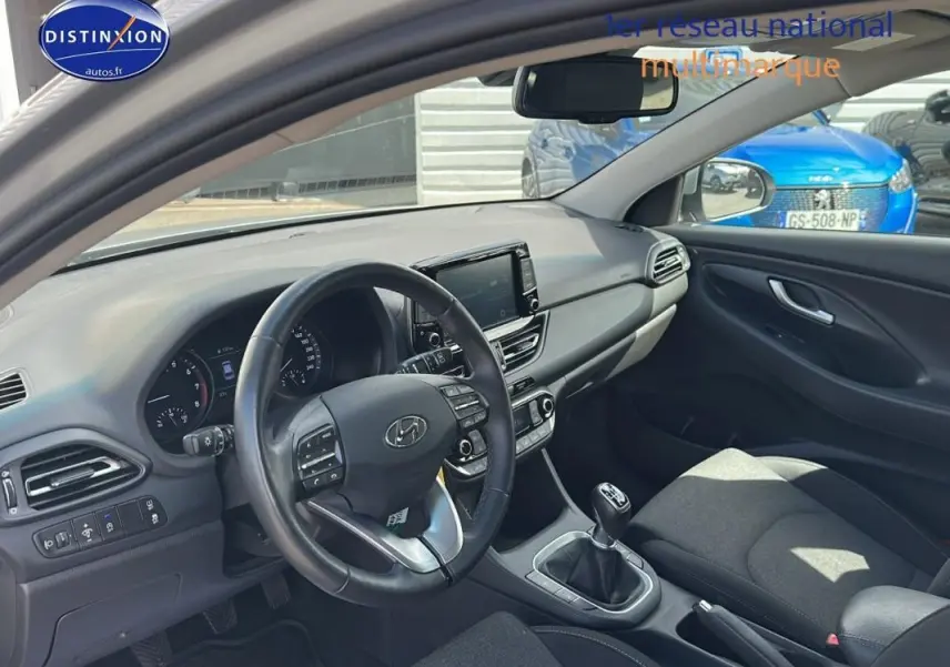 Intérieur de la Hyundai i30 SW 2022 vue côté conducteur, avec tableau de bord moderne et volant multifonction noir.