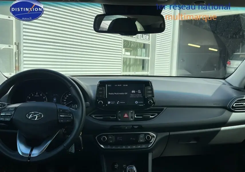 Vue intérieure du tableau de bord et volant noir de la Hyundai i30 SW 2022 avec écran tactile et commandes au volant.