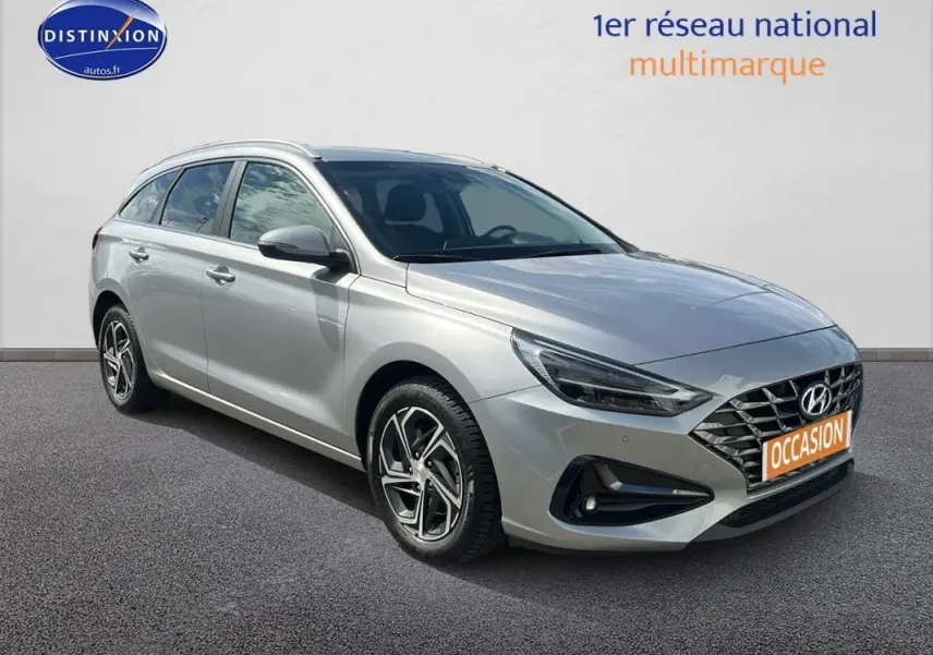 Hyundai i30 SW gris clair vue 3/4 avant droit avec jantes alliage et calandre distinctive moderne