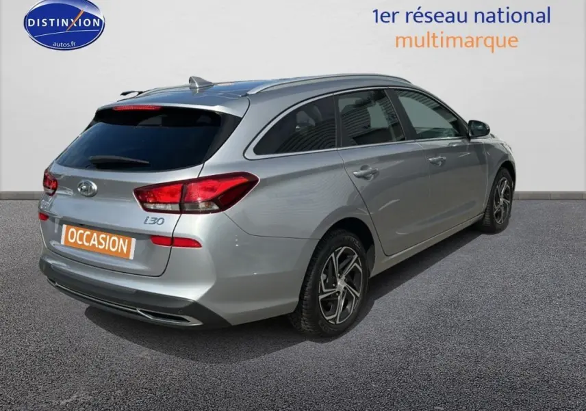 Vue 3/4 arrière droite d'une Hyundai i30 SW gris clair avec jantes alliage et vitres surteintées.