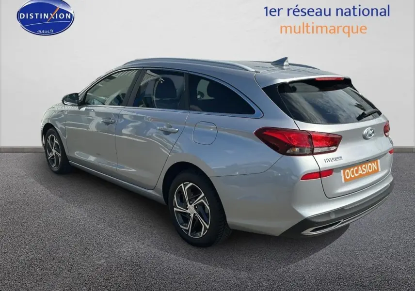 Vue 3/4 arrière droite d'une Hyundai i30 SW gris clair avec jantes alliage 17 pouces et vitres surteintées.