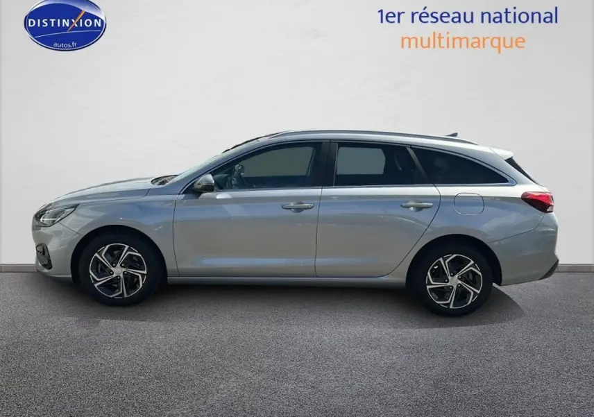 Profil latéral droit d'une Hyundai i30 SW gris clair 2022 avec jantes alliage 17 pouces et vitres surteintées.