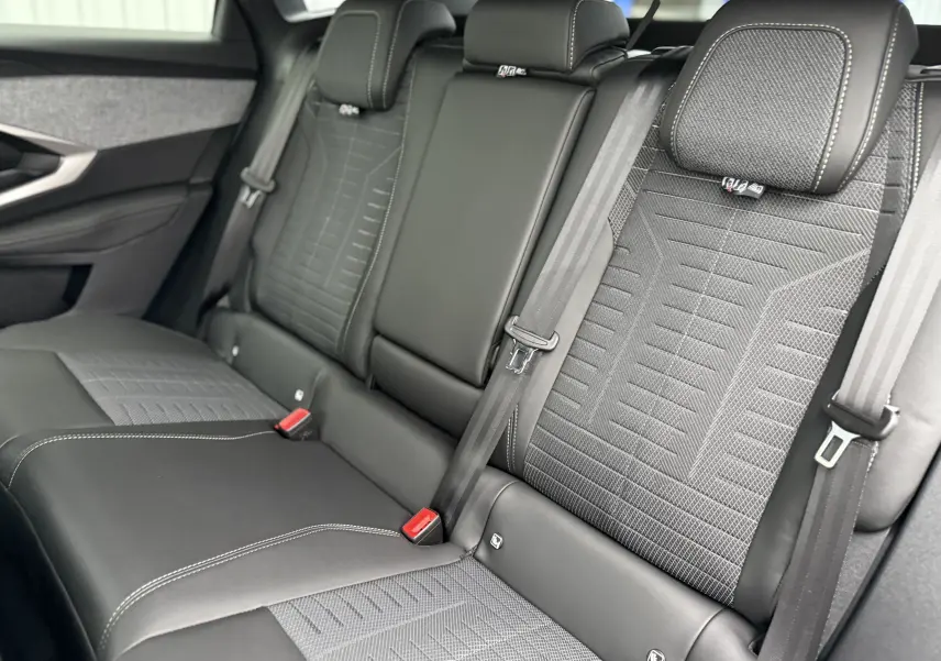 Vue rapprochée des sièges arrière en cuir noir et tissu gris du Peugeot 3008 Hybrid 2025, avec ceintures et appuie-têtes.