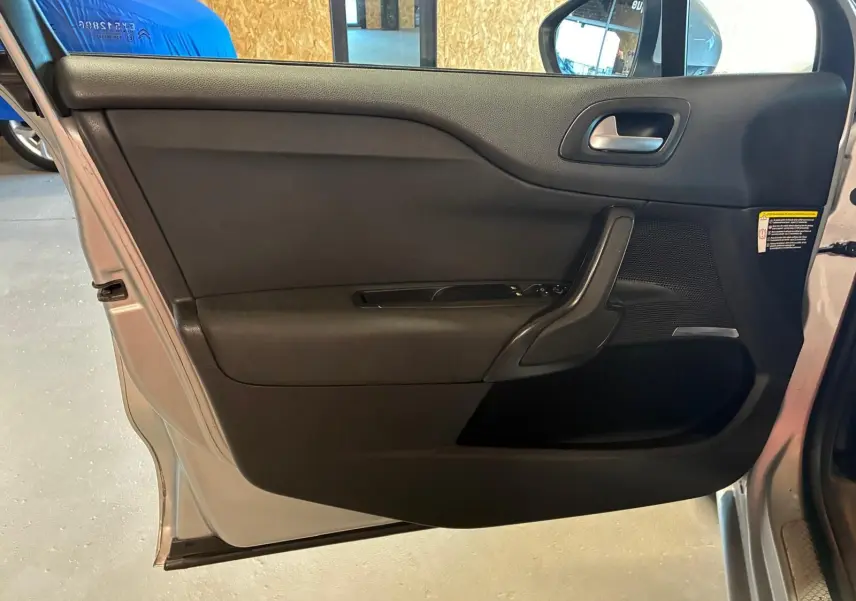 Vue intérieure côté gauche de la porte avant gris clair d’une DS4 2014 avec garniture noire et commandes de vitre.
