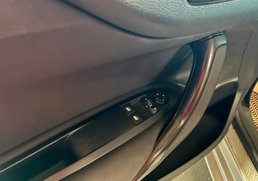 Gros plan sur la poignée intérieure et les commandes de vitres côté conducteur d’une DS4 gris foncé.