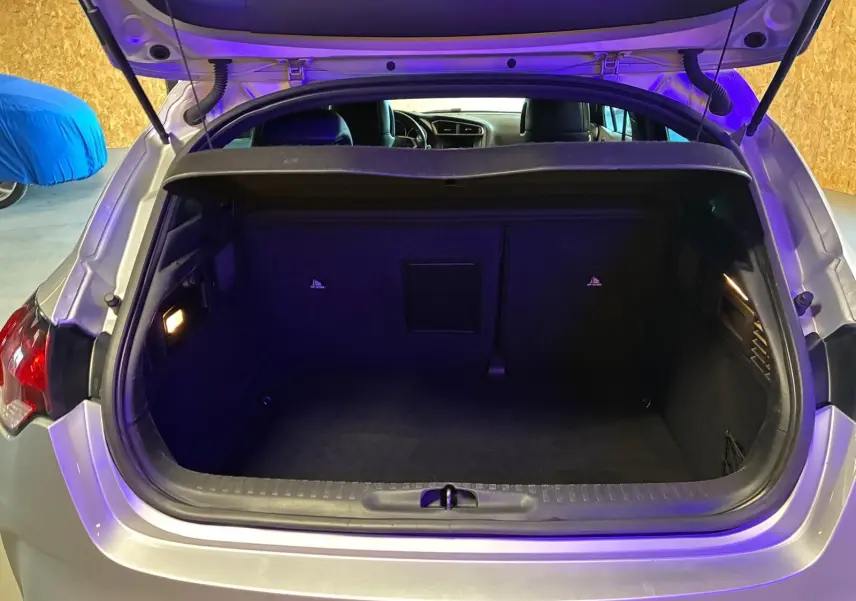 Coffre ouvert d'une DS4 gris clair vue de l'arrière, montrant un espace de chargement propre et éclairé.