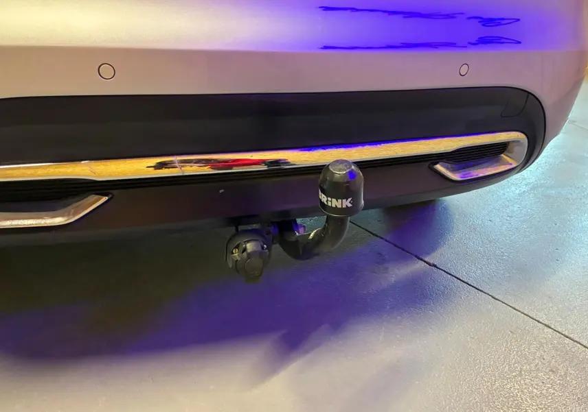 Gros plan sur l'attelage de remorque noir fixé au pare-chocs arrière gris d'une DS4 2014.