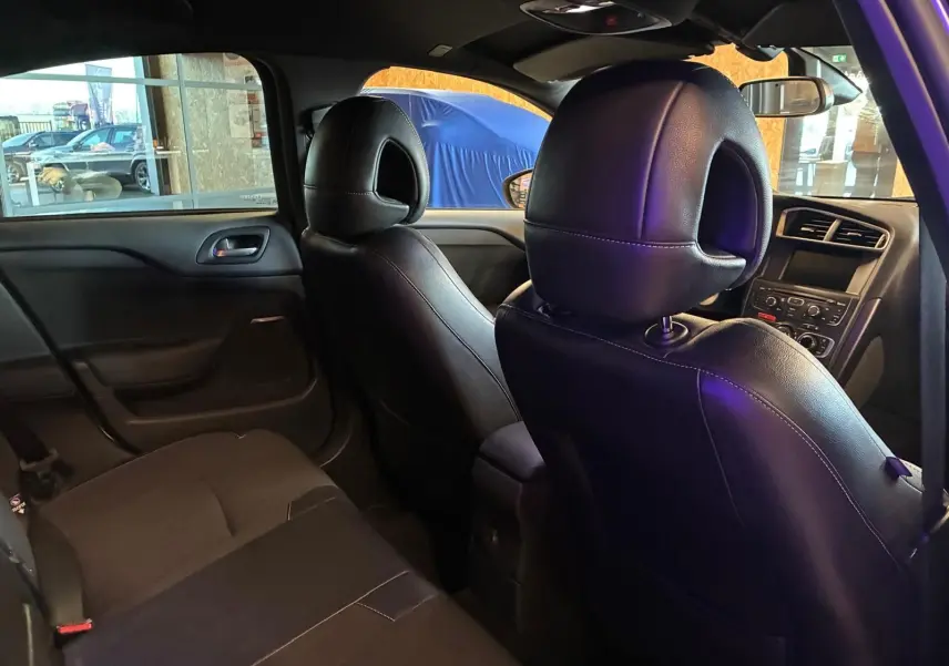 Vue intérieure arrière droite de la DS4 gris, montrant les sièges avant en cuir noir et la console centrale.