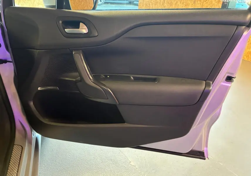 Vue intérieure de la porte côté gauche d'une DS4 gris 2014, avec poignée noire et garniture tissu gris-noir.