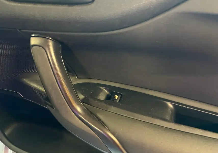 Poignée de porte intérieure côté gauche de la DS4 gris foncé, avec bouton de verrouillage intégré.