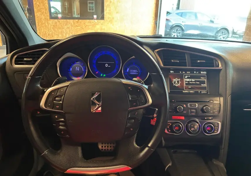 Vue intérieure centrée sur le volant et le tableau de bord du DS4 gris, avec affichage digital et commandes au volant.