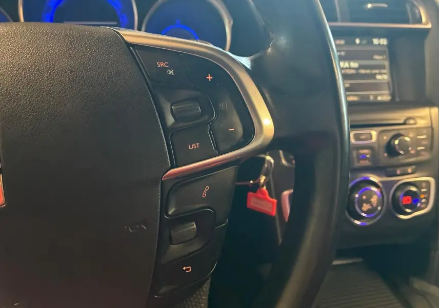 Gros plan sur le volant noir de la DS4 2014 avec commandes intégrées, tableau de bord et console centrale en arrière-plan.