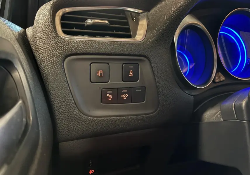 Détail intérieur côté gauche du tableau de bord gris noir du DS4 2014, avec commandes d’aide à la conduite et compteurs bleus éclairés.