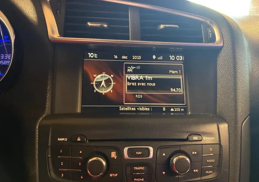 Vue rapprochée du tableau de bord de la DS4 gris, mettant en valeur l’écran central avec navigation et radio FM.