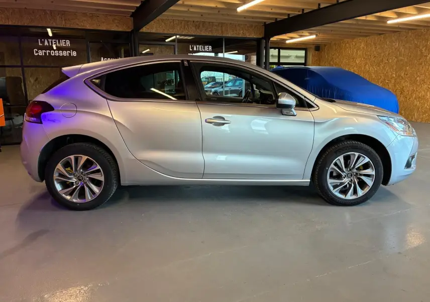 Vue latérale droite d'une DS4 gris clair 2014 stationnée en intérieur, mettant en valeur ses lignes fluides et ses jantes alliage.