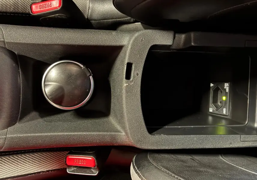 Vue rapprochée de la console centrale de la DS4 gris, montrant un porte-gobelet, un rangement et les ceintures de sécurité rouges.