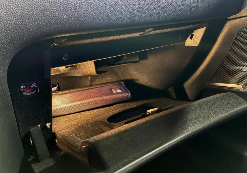 Gros plan sur la boîte à gants ouverte côté passager du DS4 gris, montrant un étui bleu à l'intérieur.