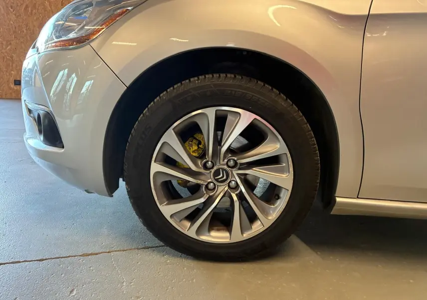 Gros plan sur la roue avant gauche d'une DS4 gris clair, mettant en valeur la jante alliage et l'étrier de frein jaune.