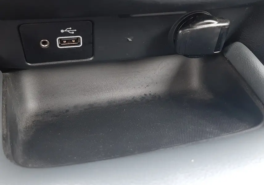 Vue rapprochée de la console centrale du Nissan Juke gris 2020, montrant une prise USB et un allume-cigare.