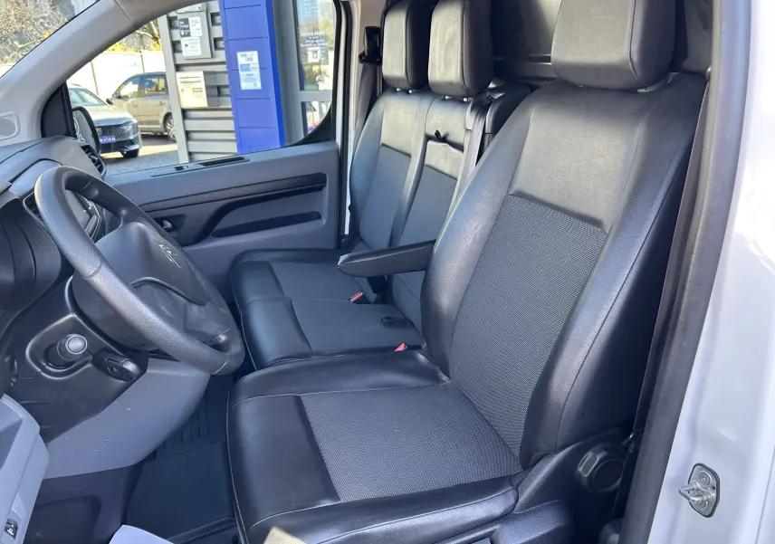 Vue intérieure côté conducteur du Citroën Jumpy blanc 2017, sièges en cuir noir et tableau de bord simple.