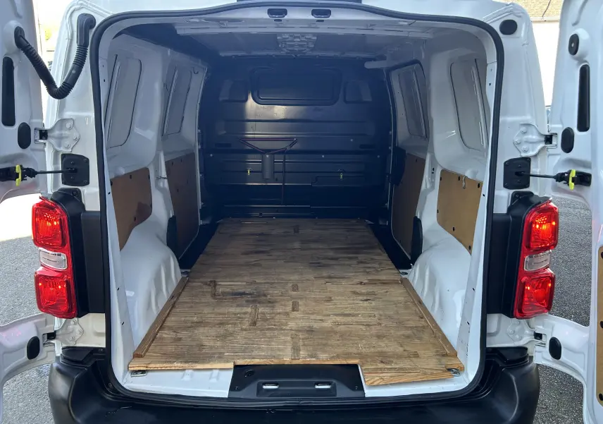 Vue arrière ouverte du Citroën Jumpy blanc 2017 montrant l’espace de chargement avec plancher en bois et parois partiellement protégées.