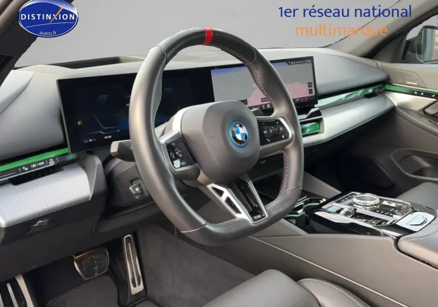 Vue intérieure côté conducteur du tableau de bord et volant cuir sport de la BMW Série 5 i5 M60 noir avec écran tactile et inserts verts.