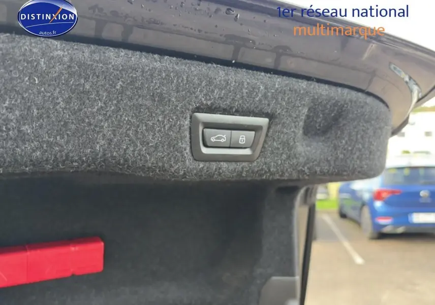 Bouton d'ouverture de coffre sur la partie intérieure du hayon d'une BMW Série 5 noire, vue rapprochée.