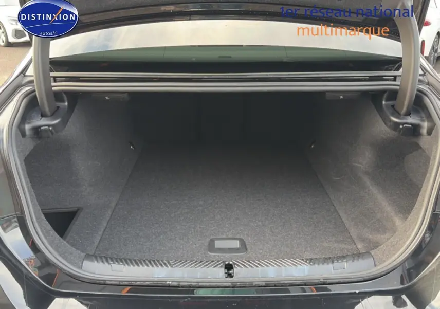 Coffre ouvert vu de l'arrière d'une BMW Série 5 i5 M60 noire, montrant un espace de rangement vide et propre.