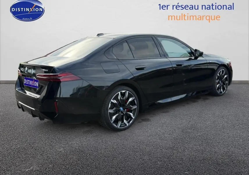 BMW Série 5 i5 M60 noir vue 3/4 arrière droit, avec jantes alu bicolores et feux arrière LED distinctifs.