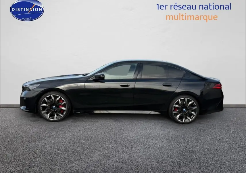 BMW Série 5 i5 M60 noir vue de profil côté gauche, avec jantes alu bicolores et étriers rouges visibles.