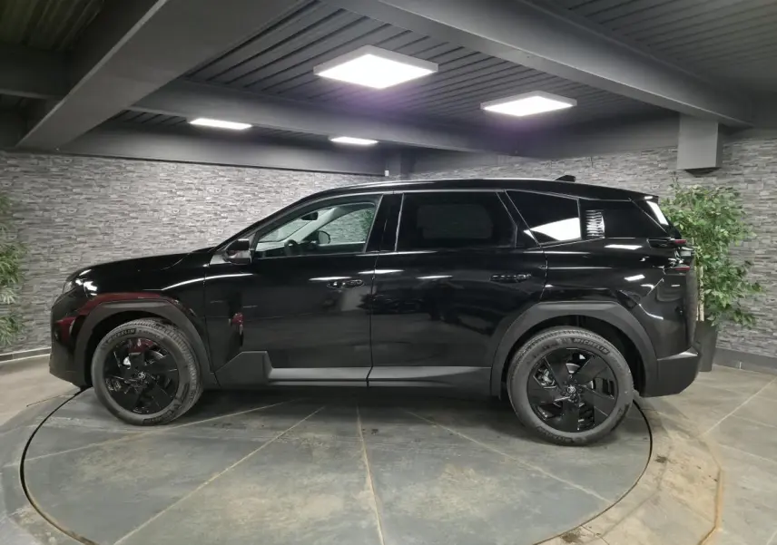 Vue latérale gauche du SUV Citroën C5 Aircross noir brillant avec jantes alliage noires dans un showroom intérieur.