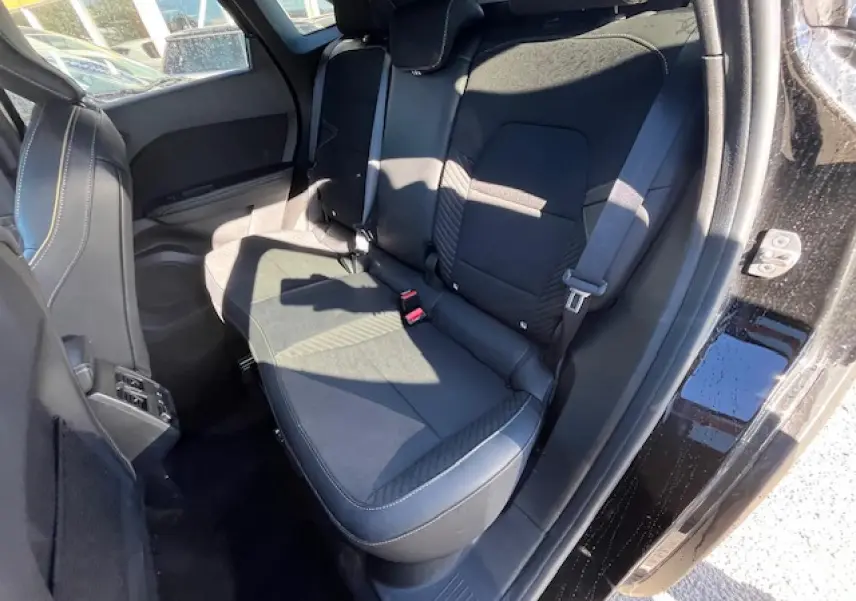 Vue intérieure côté droit sur la banquette arrière noire du Renault Symbioz 2025 avec porte ouverte et ceinture visible.