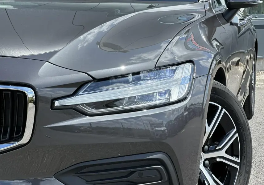 Gros plan sur l'avant droit d'une Volvo S60 gris Platinium, mettant en valeur le phare LED et la jante alliage 17 pouces.