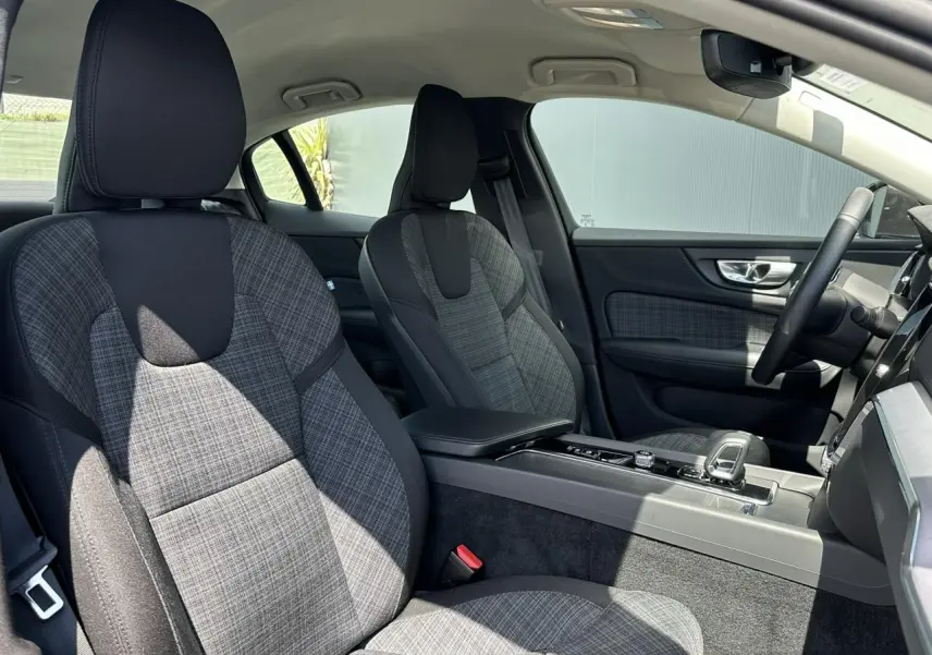Vue intérieure côté droit du Volvo S60 2024, sièges avant en tissu gris à motif tartan avec console centrale moderne.