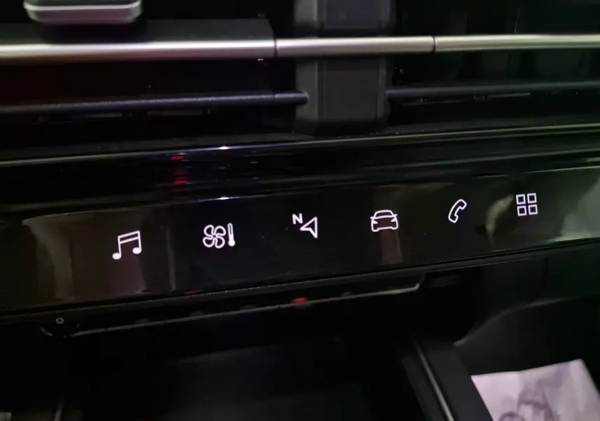 Détail de la console centrale noire du Citroën C5 Aircross 2024 avec icônes tactiles lumineuses pour musique, climatisation et navigation.