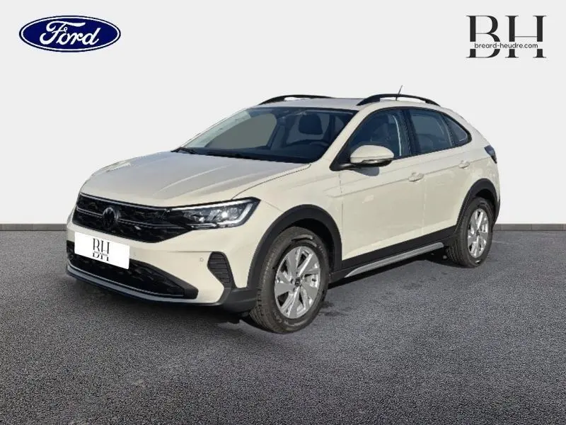 Vue 3/4 avant droite d'un Volkswagen Taigo blanc pur avec barres de toit et jantes alu sur fond neutre.