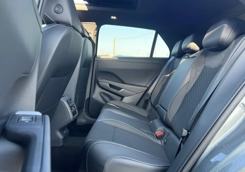 Vue intérieure arrière droite du Volkswagen T-Roc 2026 gris loup, montrant les sièges arrière en tissu et cuir avec surpiqûres blanches.