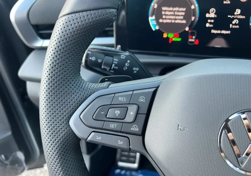 Gros plan sur le volant cuir perforé gris du Volkswagen T-Roc 2026 avec commandes multifonctions et tableau de bord numérique.