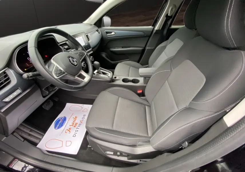Vue intérieure côté conducteur du Renault Arkana noir 2024, sièges gris et tableau de bord avec écran tactile central.