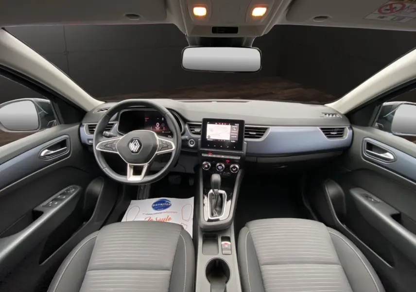 Vue intérieure avant du Renault Arkana 2024 noir, montrant le tableau de bord avec écran tactile central et volant multifonctions.