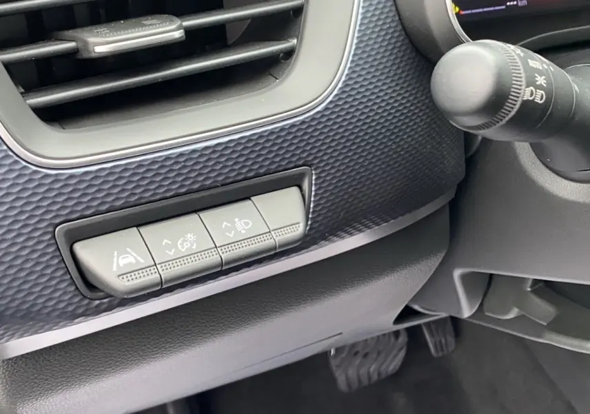 Détail intérieur du tableau de bord noir du Renault Arkana PH2 Evolution, avec boutons de réglage d'assistance à la conduite.