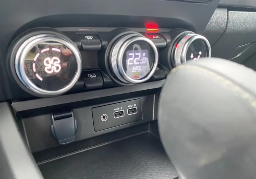 Détail des commandes de climatisation et ports USB du tableau de bord du Renault Arkana noir, vue intérieure rapprochée.