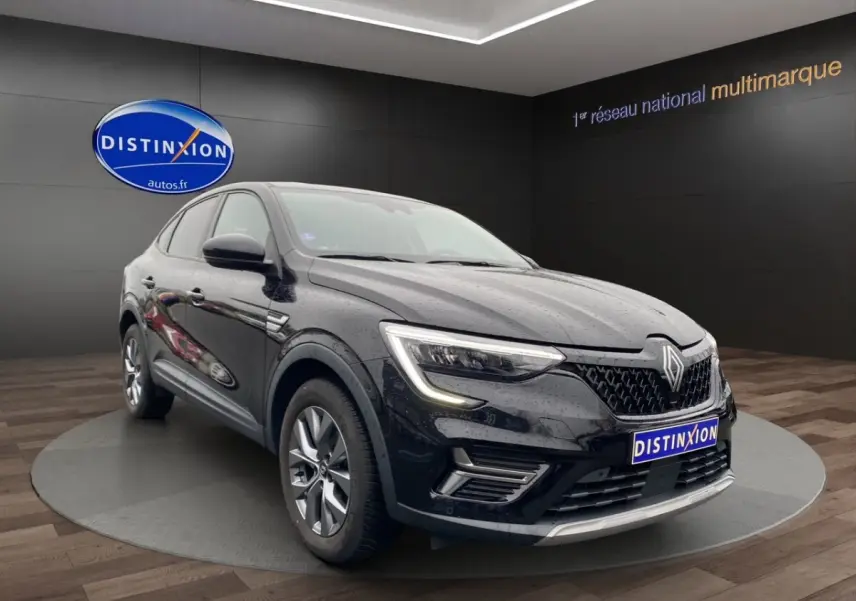 Vue 3/4 avant d'un Renault Arkana noir 2024 avec calandre distinctive et phares LED allumés en intérieur showroom.