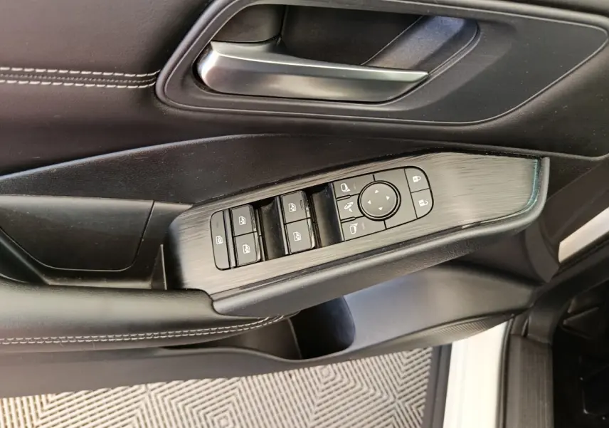 Vue rapprochée de la porte avant gauche du Nissan Qashqai blanc, avec commandes électriques des vitres et rétroviseurs.