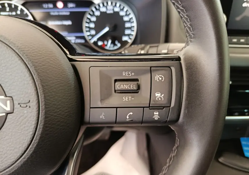 Gros plan sur les commandes du régulateur de vitesse au volant cuir noir du Nissan Qashqai e-Power 2024.