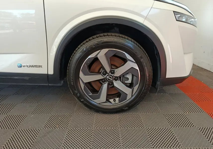 Gros plan sur la roue avant droite du Nissan Qashqai e-Power blanc avec logo e-Power sur la carrosserie.