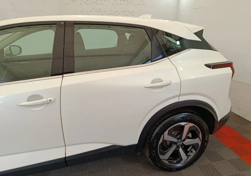 Vue latérale côté droit du Nissan Qashqai blanc 2024, mettant en valeur la roue arrière et les lignes épurées du SUV.