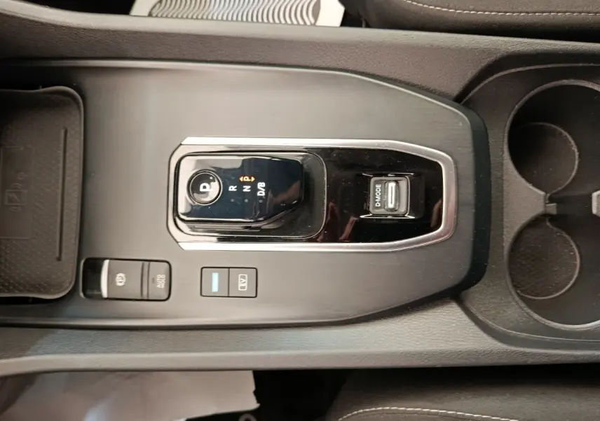 Vue rapprochée de la console centrale noire du Nissan Qashqai e-Power 190 Business Edition avec sélecteur de boîte auto et boutons de mode.